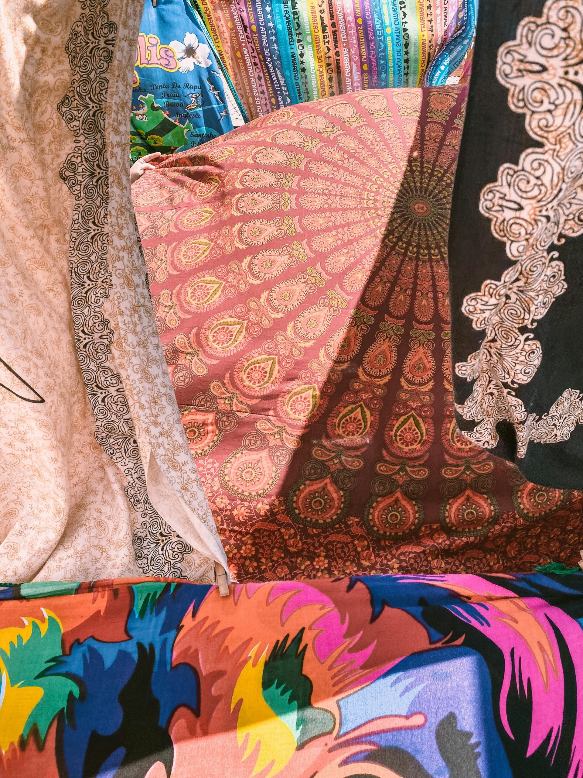 Vibrant fabrics on display in Florianópolis market, showcasing intricate patterns and colors.