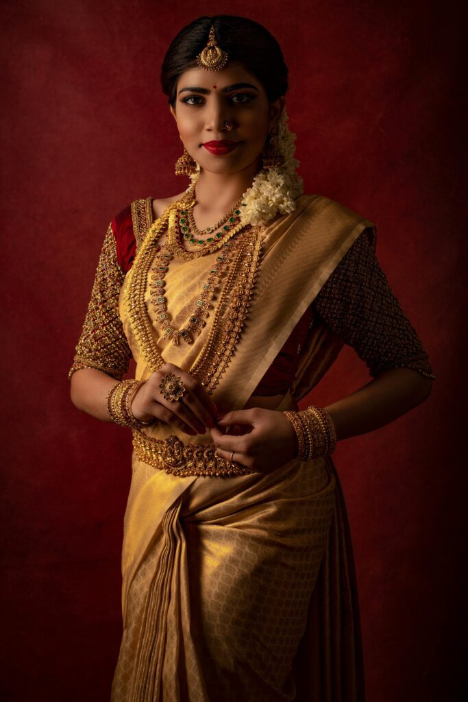 A beautiful Indian bride in a golden saree adorned with traditional jewelry, captured in a studio setting.