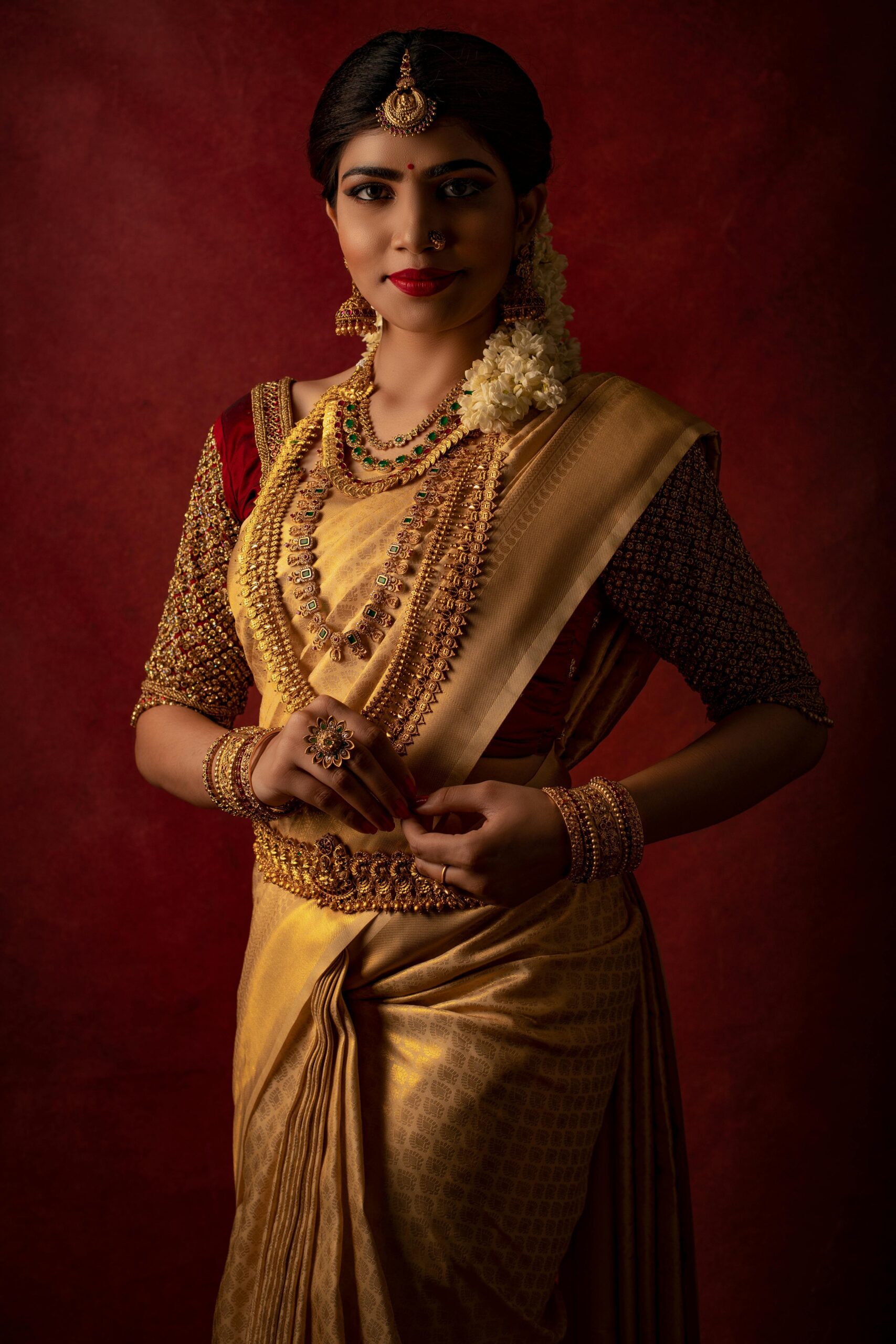 A beautiful Indian bride in a golden saree adorned with traditional jewelry, captured in a studio setting.