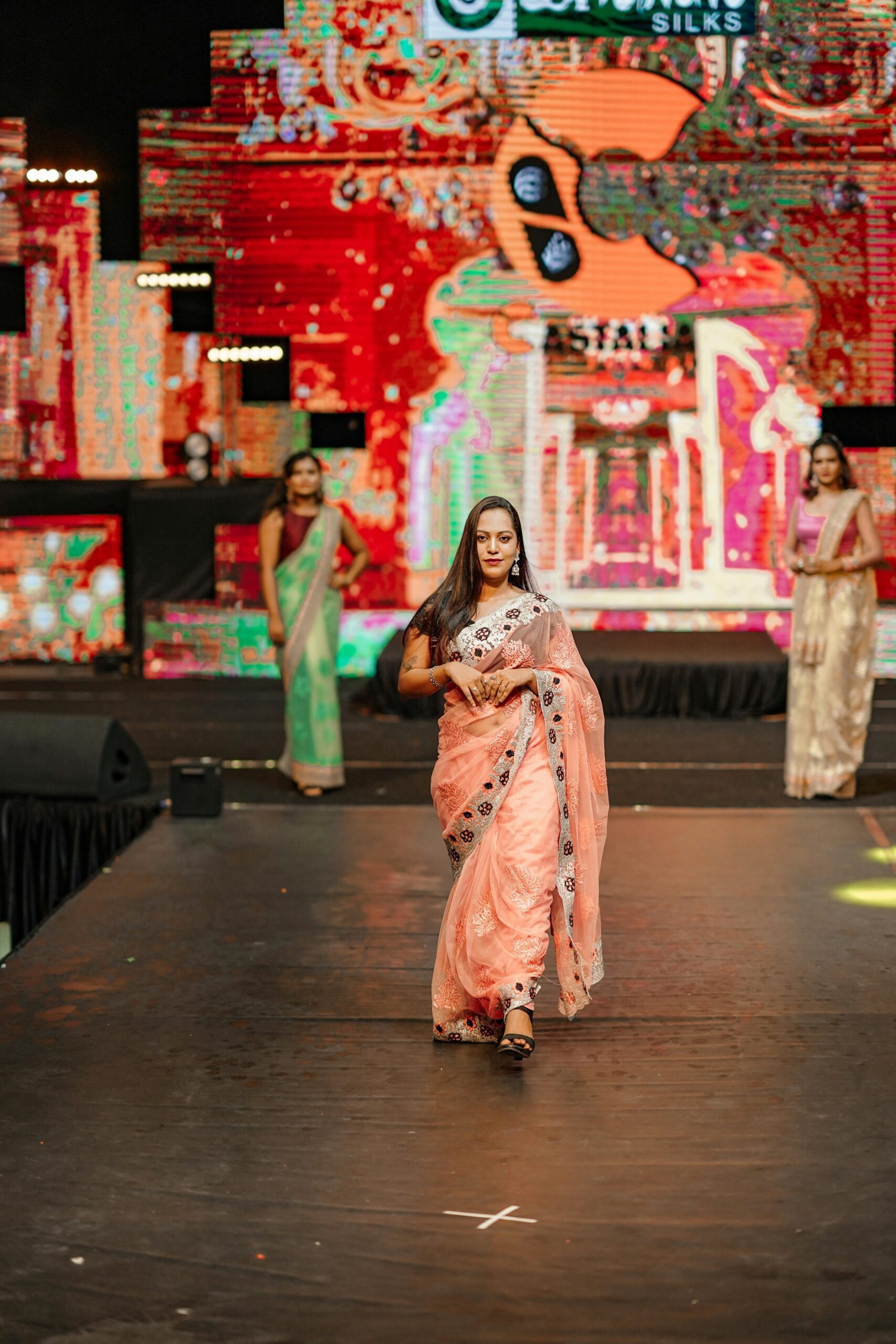 Elegant models showcasing traditional sarees on a vibrant fashion runway.
