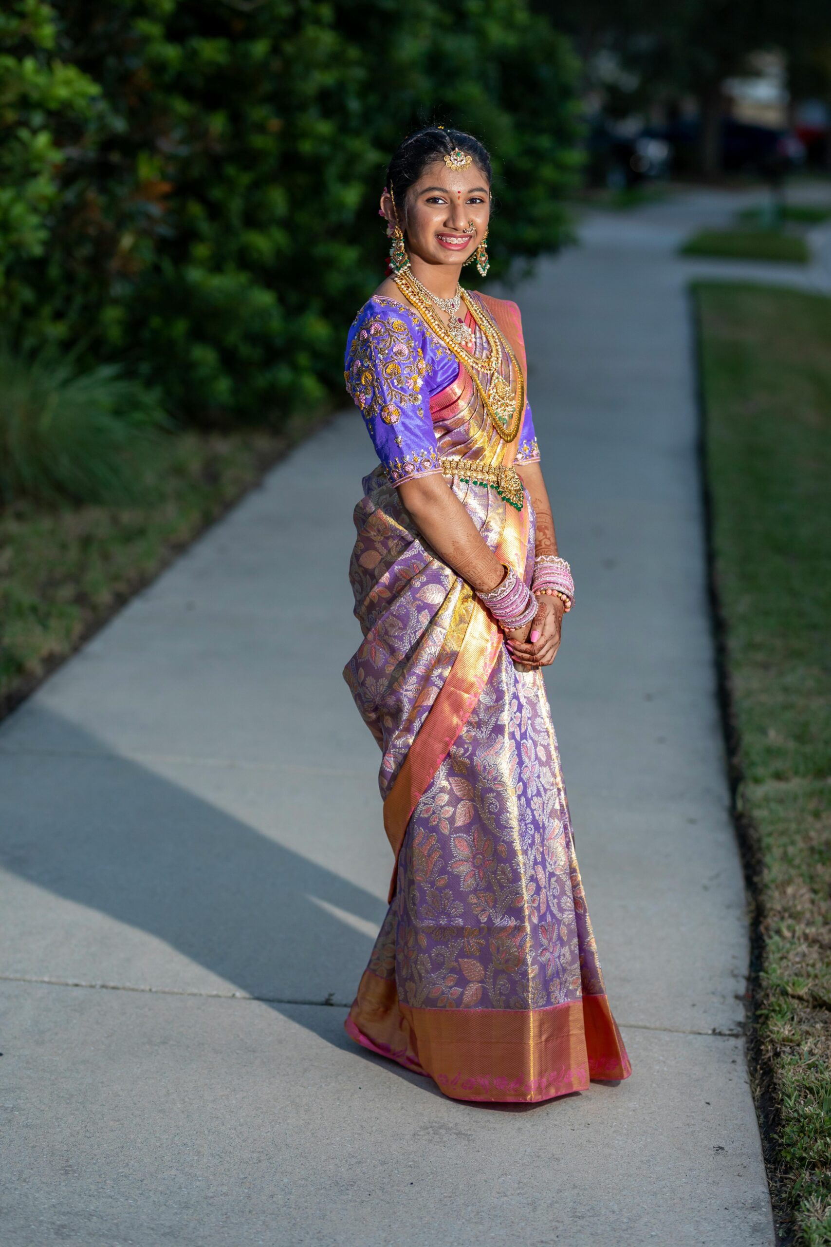 A woman poses outdoors in a colorful traditional saree, showcasing cultural fashion.