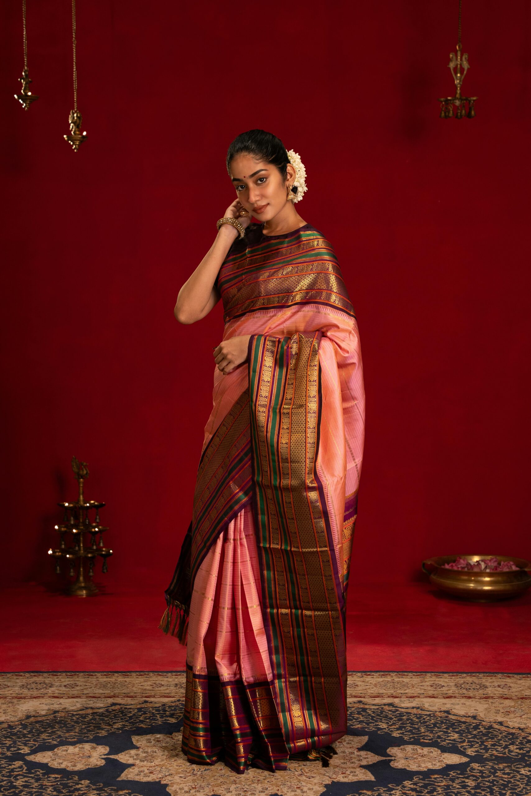 Elegant Indian woman in traditional saree with rich colors, standing in a cultural setting.