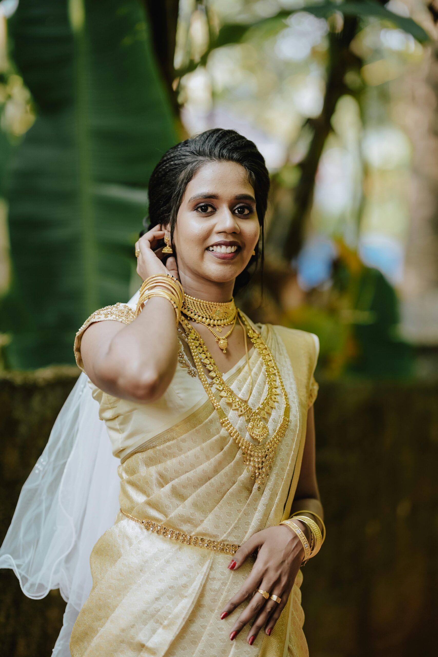 A beautiful Indian bride smiling in a traditional gold saree, adorned with jewelry.