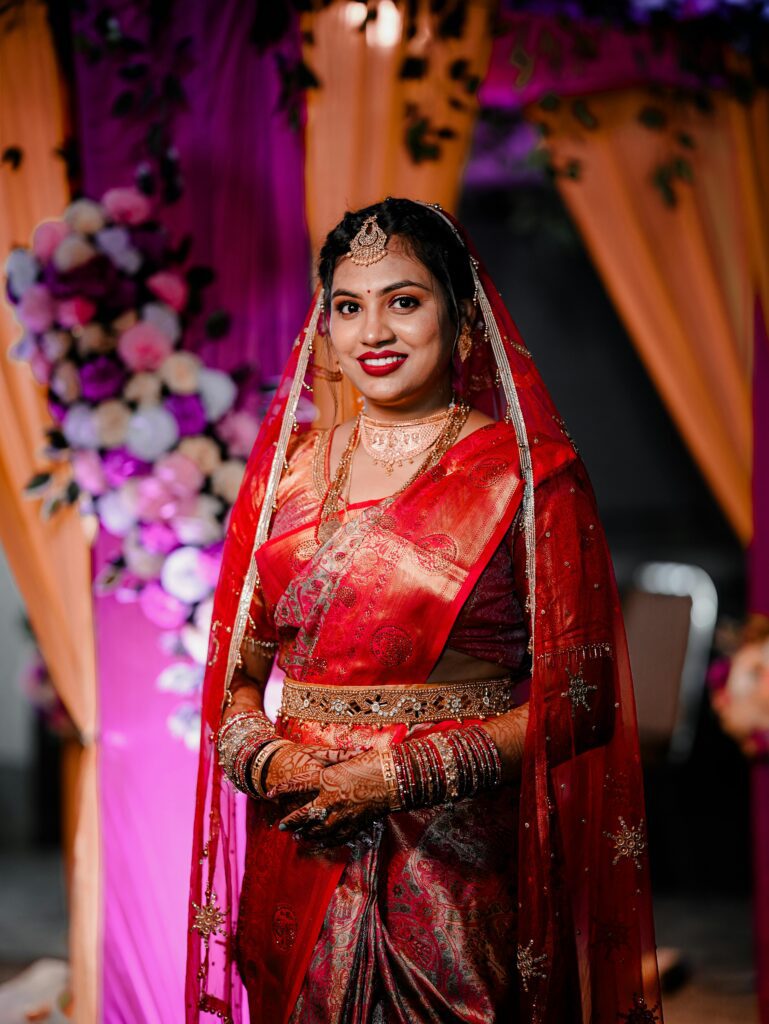 Elegant Indian bride in red saree with intricate accessories at a wedding in Brahmapur, India.