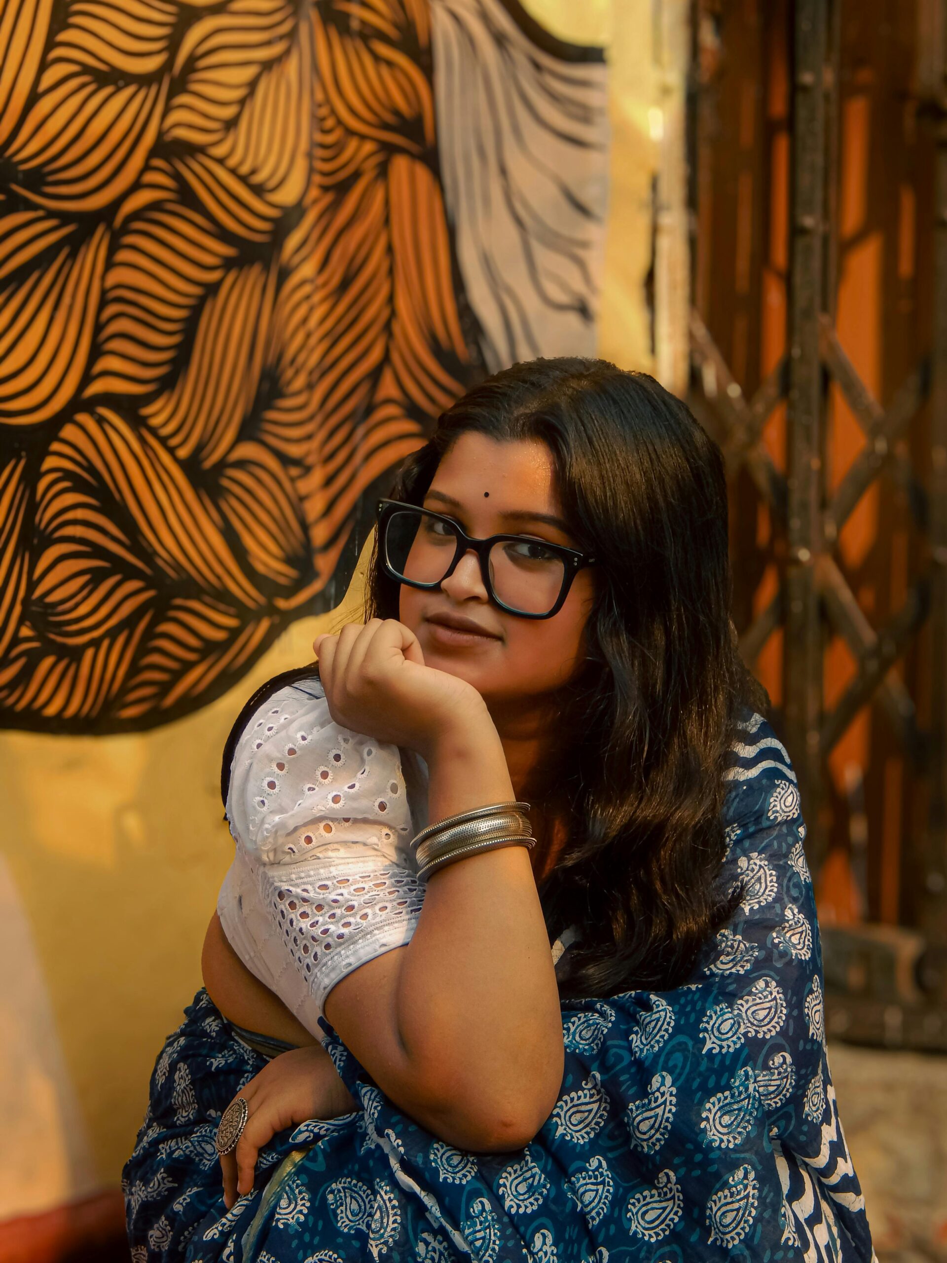 Artistic portrait of a woman wearing a colorful saree and glasses, in India.